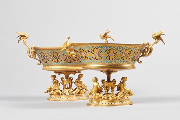 A pair of Napoleon III gilt bronze and enamel tazza, circa 1870, each of tapering oval form, with bird cast handles and putto beneath on a shaped foot