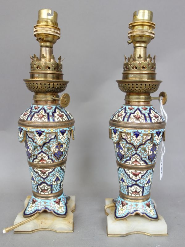 A pair of French champlevé enamel oil lamps, converted, circa 1880, each raised on a shaped hardstone plinth, 22cm high , excluding fitment, (2).  Ill
