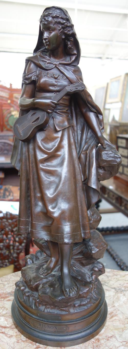 After Eutrope Bouret (French 1833-1906); a French bronze figure 'The Woman with the Guitar', titled 'Mignon' and dated 1910, on a naturalistic rocky b