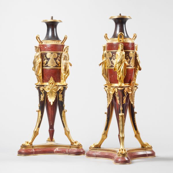 A pair of French rouge marble, ormolu mounted pedestals, in the Empire style, each of three handled urn form flanked by classical figures on three lio