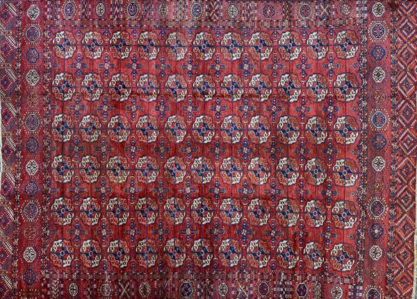 A Tekke Turkman carpet, the madder field with six columns of eleven guls, supporting bee crossed, a sunburst border, skirt ends, 280 x 202cm.  Illustr