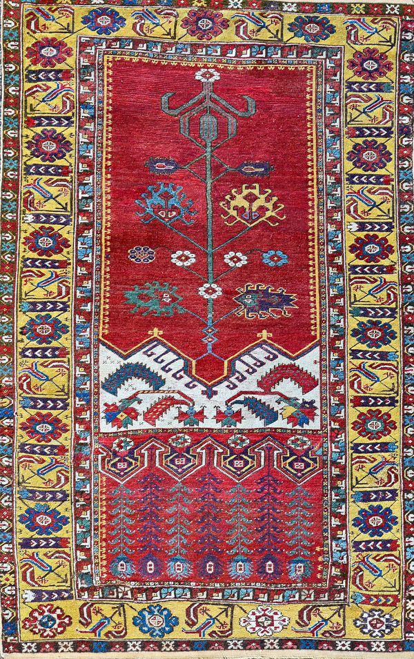 An antique Ladik prayer rug, the madder mihrab with a delicate flowering plant, madder and ivory arch, a saffron flowerhead and tulip border, 166cm x