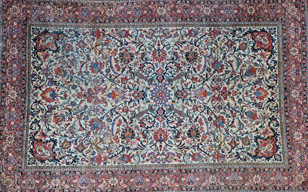 A Esfahan carpet, Persian, the ivory field with a central indigo rosette, all with trailing floral sprays, deer and various birds, a madder and floral