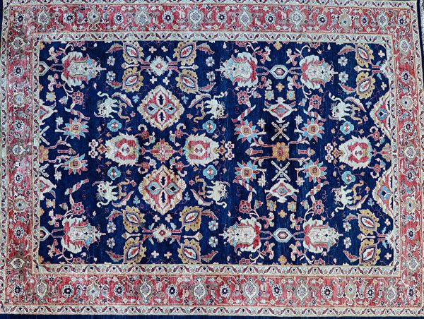 A Tabriz carpet, Persian, the dark indigo field with allover design, with bold ivory palmettes, flowers, pair of stylized lions, a madder palmette bor