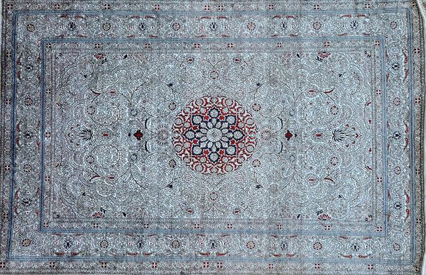 A fine silk Hereke mat, Turkish, the ivory field with a madder rosette, intricate vine spray, a complementary border, 94cm x 60cm.   Illustrated