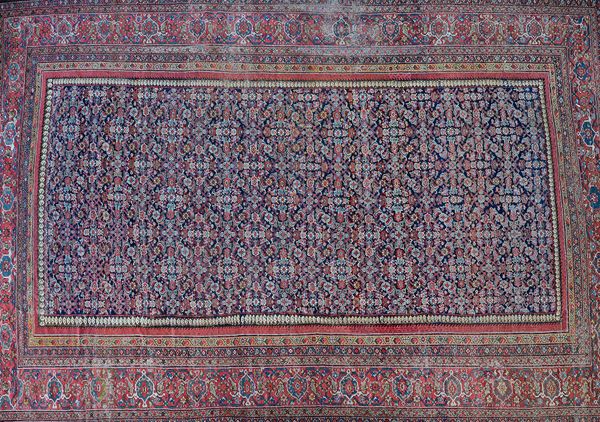 A Fereghan carpet, early 20th century, dark blue field with all over Herati design within a wide palmette main border and multiple guard strips, 328cm