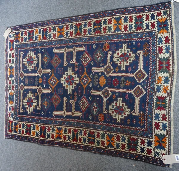A Shirvan rug, Caucasian, the indigo field with central ivory medallion, ivory angular brackets, minor motifs and five ivory flowerheads, an ivory flo