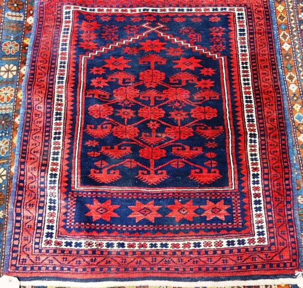 A Belouche prayer rug, the indigo mehrab with a madder flowering tree, madder stars beneath.