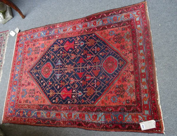 A Hamadan rug, Persian, the indigo field fitted with angular flowering branches, madder spandrels with flowering plants, an indigo waved vine border,