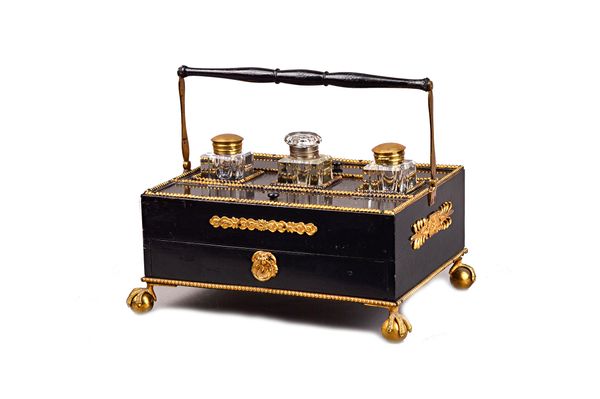 A French Empire style gilt metal mounted ebonised desk stand, the swingover handle above a trio of inkwells, pair of lift top compartments and single