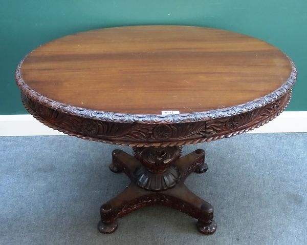 A 19th century Anglo-Indian carved hardwood centre table, the circular snap top on carved bulbous column, quatrefoil platform and melon carved feet, 1