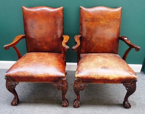 A pair of George III style open armchairs, each with studded rouge leather upholstery, on mahogany claw and ball feet, 70cm wide x 100cm high, (2).
