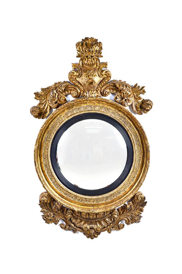A mid-19th century gilt framed convex wall mirror, the cartouche crest with acanthus sprays over reeded ebonised slip and wavy gadrooned carved frieze
