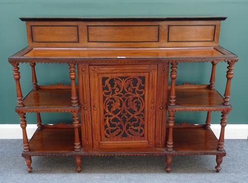 A 19th century Anglo-Indian satinwood and hardwood side cabinet, with central pierced and carved door, flanked by open shelves on turned supports, 152