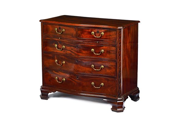 A mid-18th century mahogany serpentine chest of two short and three long graduated drawers, flanked by canted blind fret corners, on square outstepped