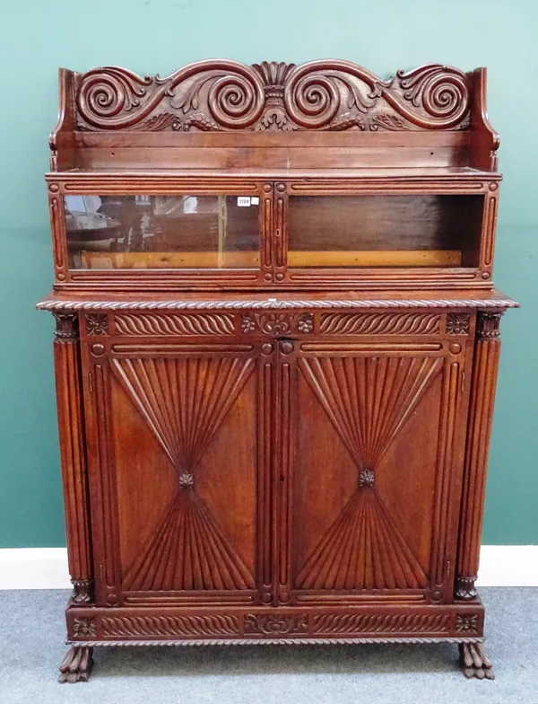 A pair of mid-19th century Anglo-Indian teak side cabinets, each with scroll back over pair of glazed doors, the base with a pair of reeded hour glass