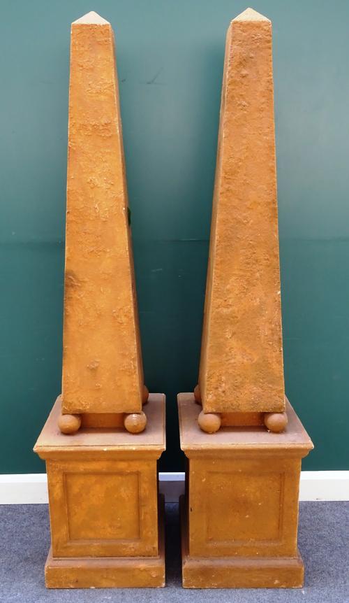 A pair of faux sandstone obelisks, each on four spherical supports and stepped square base, 47cm wide x 205cm high, (2).
