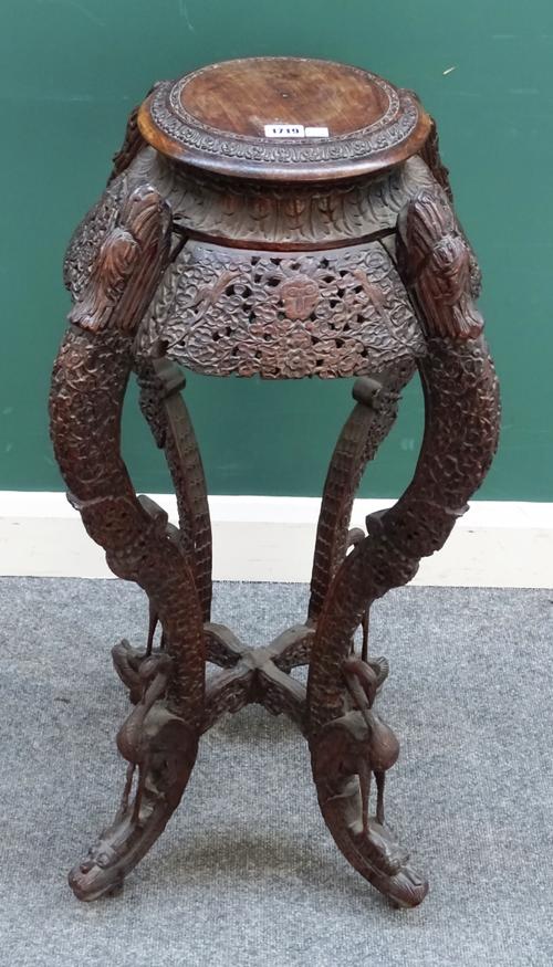 A 19th century Burmese extensively carved hardwood jardiniere stand, the circular top on four bird mounted scroll supports, united by 'X' frame stretc