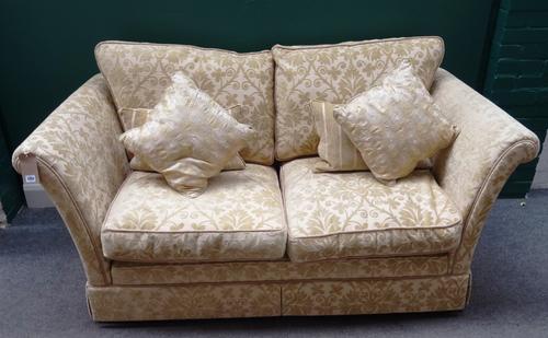 A 20th century square back two seater sofa, with outswept arms and gold stylised floral pattern upholstery, 185cm wide x 93cm deep x 80cm high.