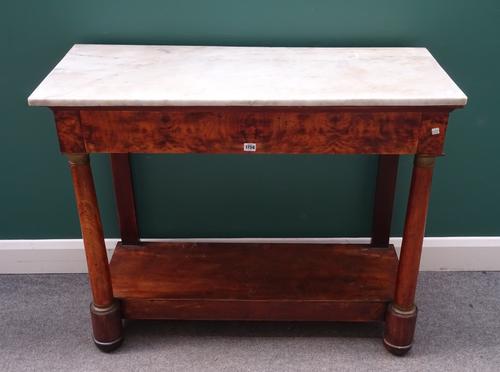 An early 19th century French console table, the rectangular marble top over a figured elm single drawer base, with gilt metal mounted turned columns u