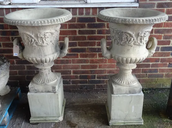 A set of four reconstituted stone twin handled jardinieres, with relief moulded foliate bodies and fluted socles, on square pedestals, 64cm diameter x