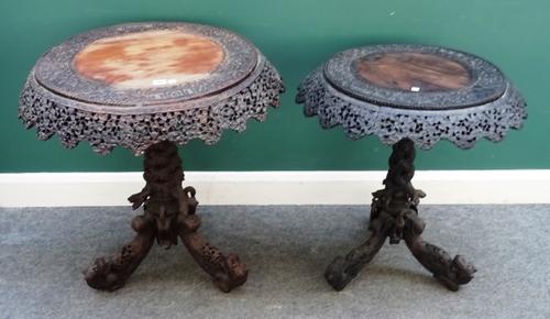 A near pair of early 20th century Burmese profusely carved hardwood occasional tables, each with foliate pierced frieze and serpent entwined columns,
