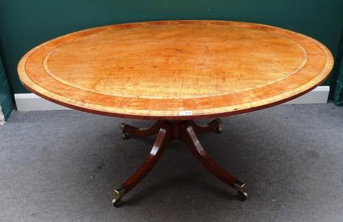 A George III breakfast table, the oval satinwood banded snap top on a turned and reeded column and four downswept supports, 161cm wide x 124cm deep x