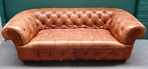 A brown leather button upholstered Chesterfield sofa, with roll-over arms on turned supports, 198cm wide x 70cm high x 95cm deep.