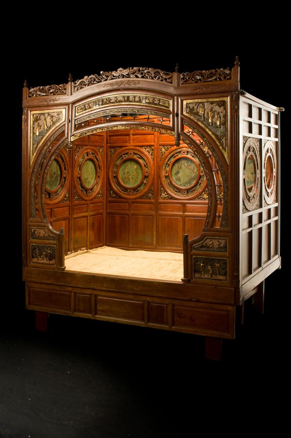 A late 19th/early 20th century Chinese red lacquer parcel gilt opium bed, mounted with seven panels within pierced roundels, resting on block supports