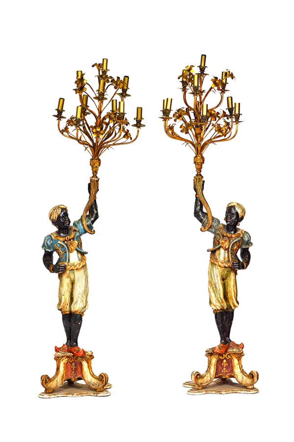 A pair of 20th century polychrome painted Blackamoor candelabra, each modelled in a standing pose, holding a ten branch candelabrum, on a shaped trian