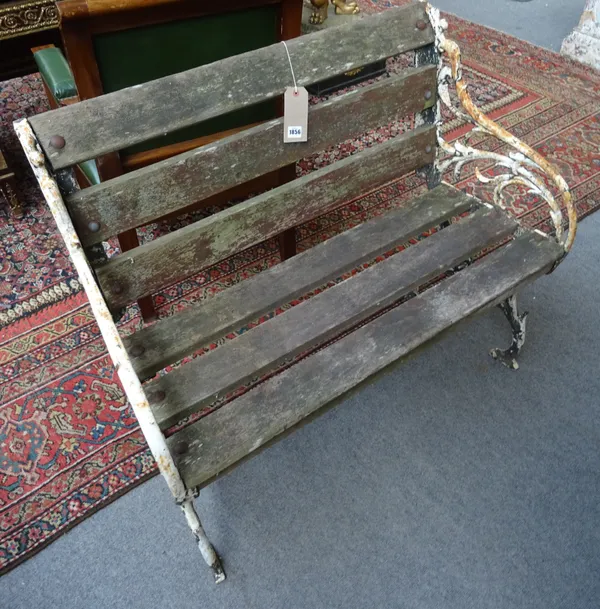 A 19th century green and white painted garden bench, with naturalistic cast iron ends, united by wooden slats, 107cm wide x 87cm high.