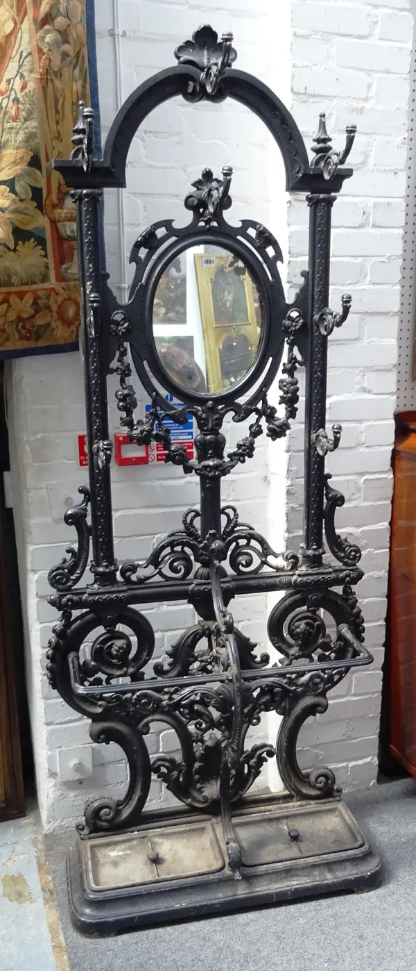 A 20th century black painted cast iron hall stand, with oval mirror back over pair of stick stands, 91cm wide x 217cm high.