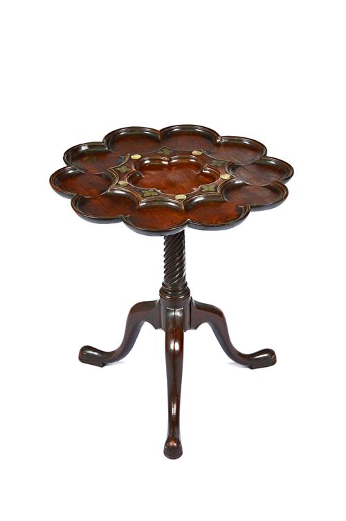In the manner of John Channon or Frederick Hintz; a George III mahogany tripod table, the shaped top with ten lobed scalloped dishes, mounted with flo