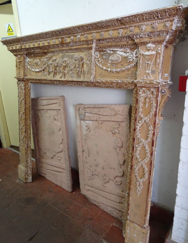 An 18th century stripped pine fire surround, with central tablet relief carved with cherubs amongst ribbon tied bell flower swags and textile draped u