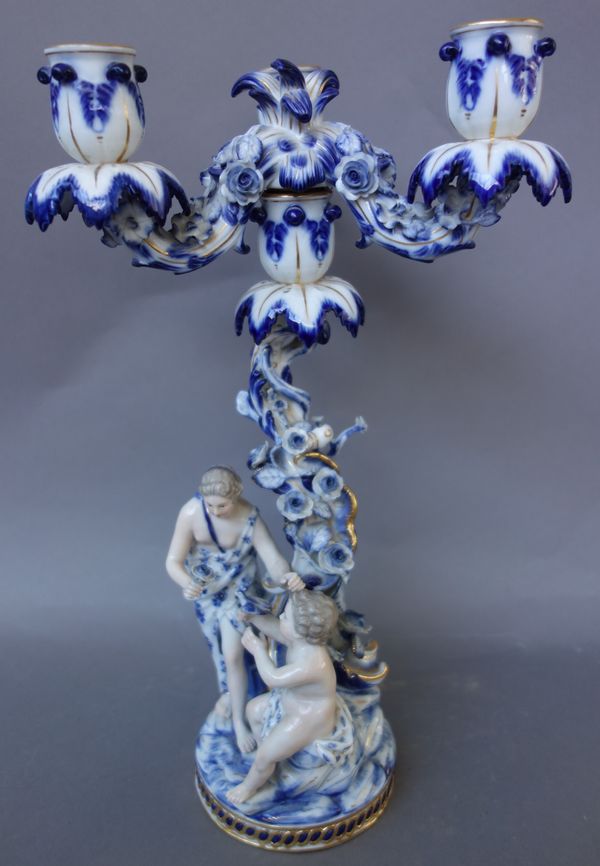 A Meissen porcelain blue and white, figural three branch candelabra, late 19th century, impressed 1197 and blue crossed swords mark, emblematic of Spr