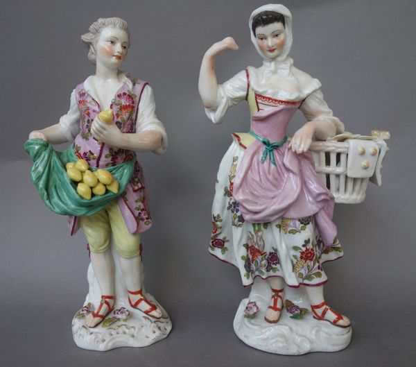 A pair of German porcelain figures, late 19th century, modelled as market traders with lemons and bread (19.5cm high) a pair of porcelain candlesticks