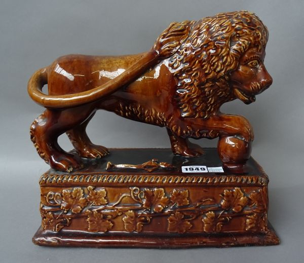 A pair of Staffordshire treacle glaze Medici lions, 19th century, each raised on a foliate moulded rectangular plinth, (29cm wide) and one smaller sim