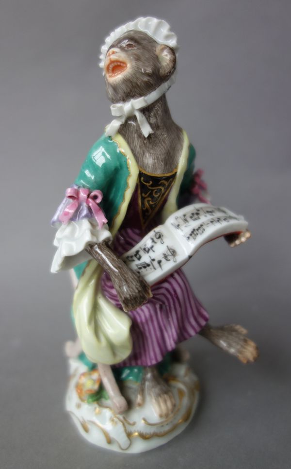 A Meissen porcelain monkey band figure, early 20th century, modelled holding sheet music on a gilt foliate scroll base, blue crossed swords mark. (a.f