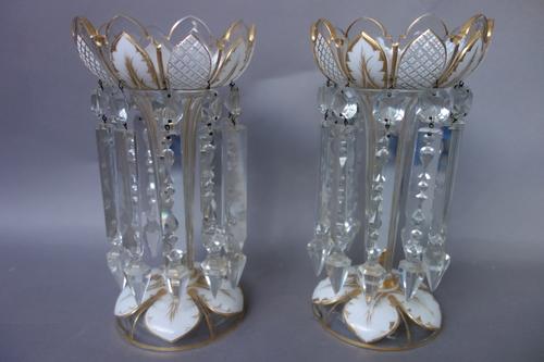 A pair of glass table lustres, late 19th century, each overlaid in white with petal shaped panels picked out in gilding and hung with prism drops, 27.