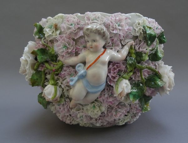 A German porcelain jardiniere, circa 1900, applied in high relief with two putti amongst densely packed flowers, 18cm. high.