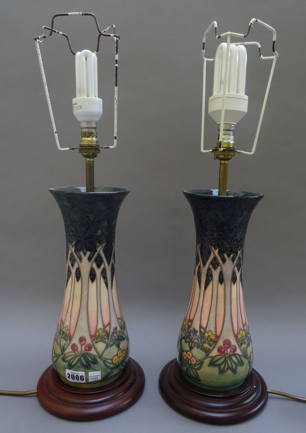 A pair of modern Moorcroft table lamps, decorated in the `Cluny' pattern, on turned wooden bases and with silk shades, the vases 30cm high, (2).