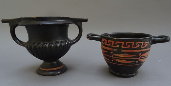 A South Italian black glazed skyphos, circa 300 B.C., decorated in red with a band of leaves and berries beneath a key pattern border, 8cm. high; also