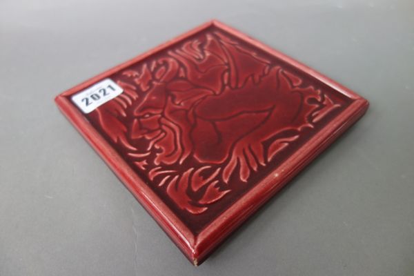 A.J.C Edwards pictorial tile, red ground, relief moulded with a dual anthropomorphic picture and raised on four moulded feet, detailed 'JC Edwards Rua