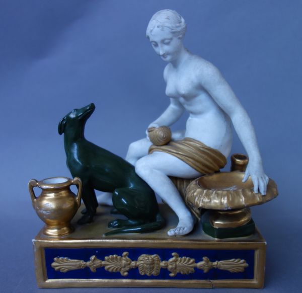 A Paris porcelain figural inkwell, 19th century, modelled with a naked female and greyhound, on a foliate moulded rectangular base (15cm wide), and a