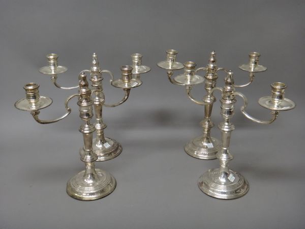 A set of four silver two light table candelabra, each with scrolling arms and raised on a circular base, (loaded), height 32cm, London 1989, retailed