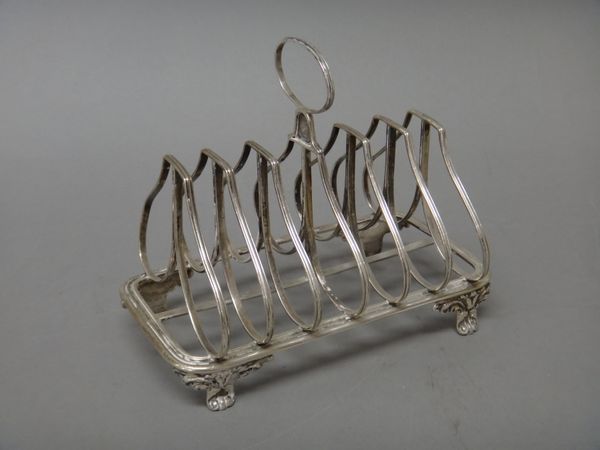 A Victorian silver seven bar toast rack,of shaped form with an oval loop shaped handle, raised on four foliate feet, London 1851, weight 303 gms.   Il