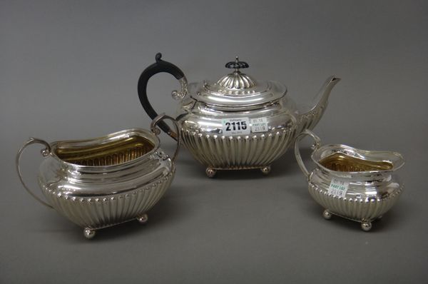 A silver three piece tea set, comprising; a teapot, a twin handled sugar bowl and a milk jug, each with partly fluted decoration, the teapot with blac