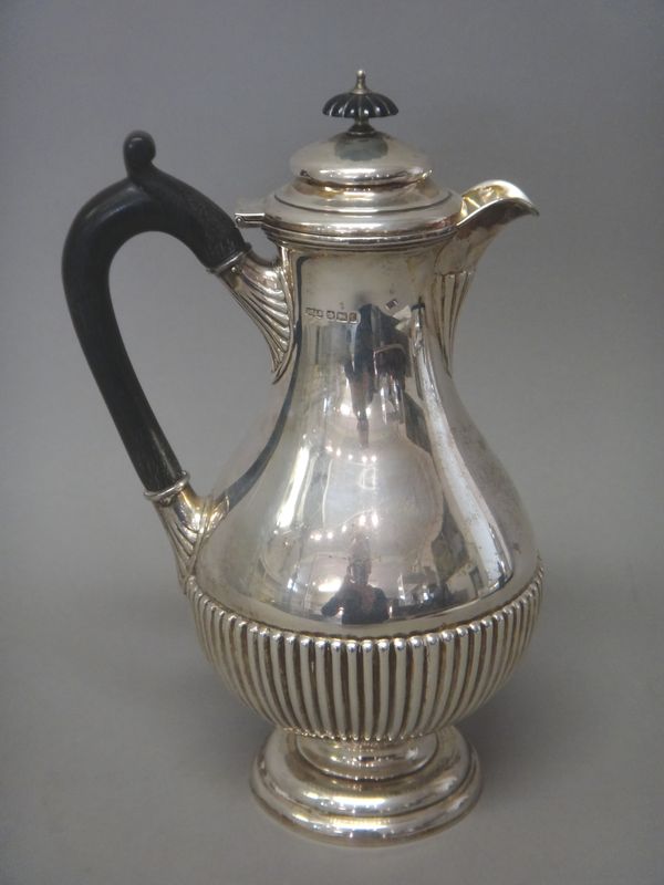 A late Victorian silver hot water jug, of baluster shaped form, with partly fluted decoration, with black fittings, raised on a circular foot, Sheffie