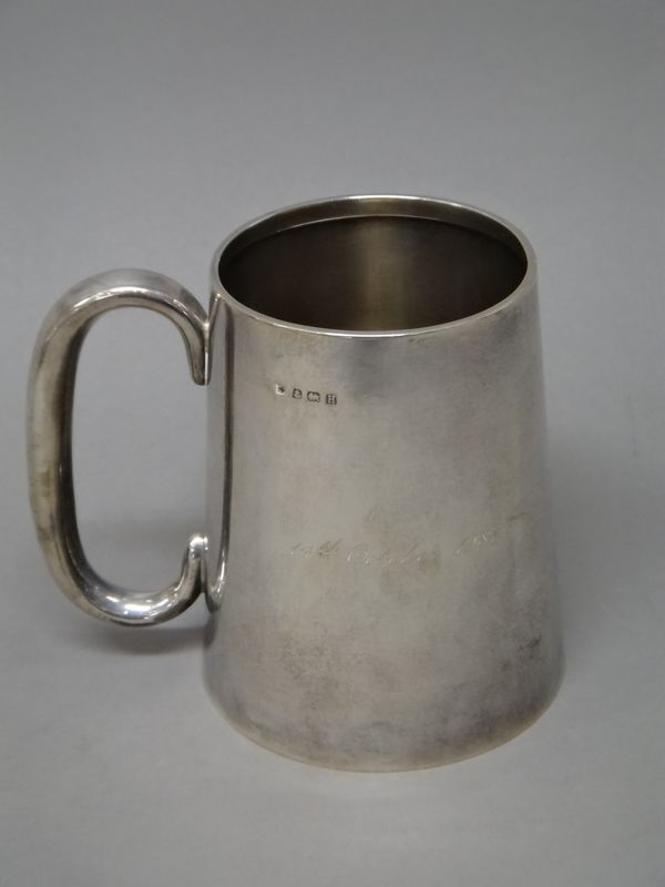 A silver mug, of tapering cylindrical form, with a 'C' shaped handle, presentation inscribed, height 11.2cm, Birmingham 1932, weight 268 gms.