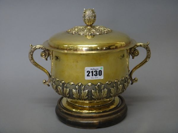 A silver gilt twin handled bowl and cover, the base decorated with a foliate band and with foliate capped scrolling handles, on a circular base, the d